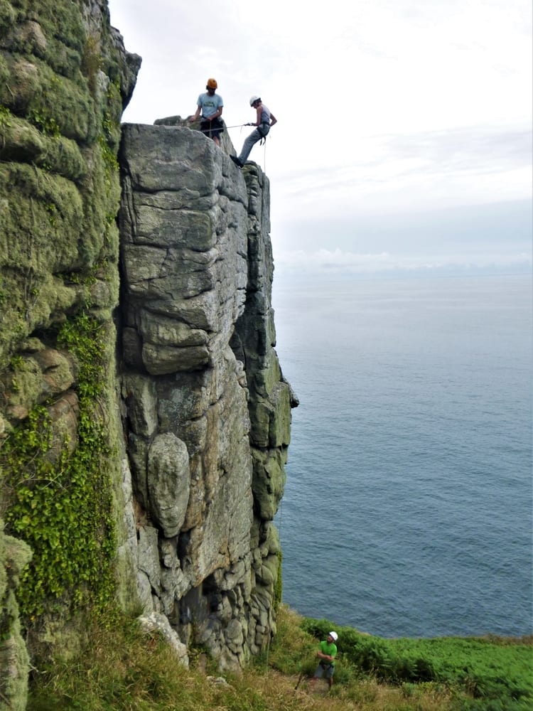 Learn abseiling and other essential rock climbing skills in Cornwall with Kernow COasteering. Here ciber abseils down a cliff in