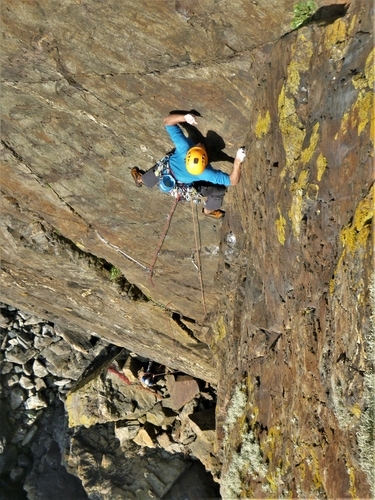 Kernow Coasteering climbing instructor leading Thane, E1, at Kenidjack Cliff, Cape Cornwall, UK.