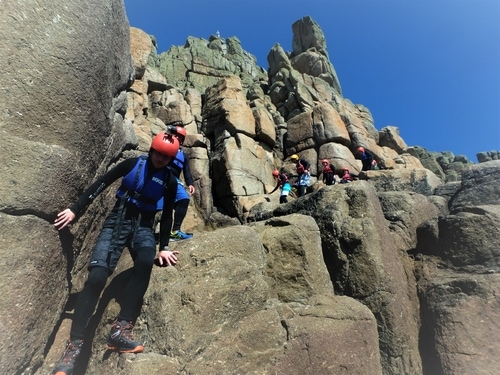 Groups beginner their adventure coasteering at Land's End Cornwall. Descending the incredible cliffs ready for the first cliff j