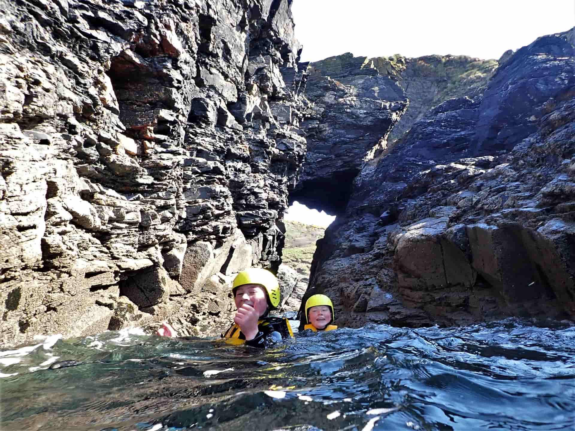 Coasteering group going through an impressive sea arch at Praa Sands, Cornwall