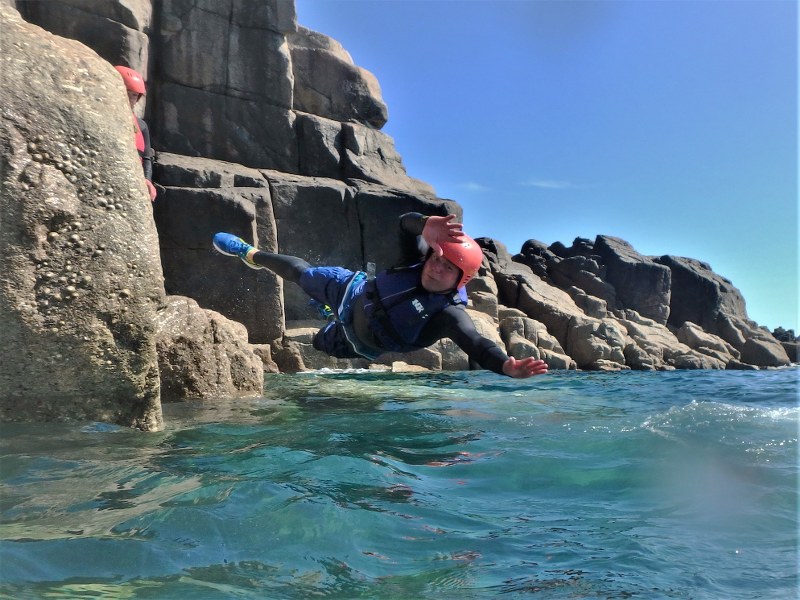 Diving into the water whilst coasteering at Land's End in Cornwall