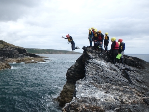 Cliff jumping on a small island during a coasteering session at Praa Sands, near Porthleven and Penzance in Cornwall, UK.