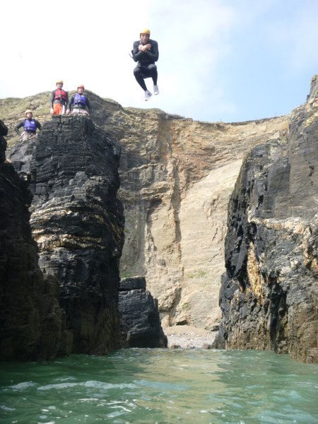 Coasteerer jumping with excellent style into a gully at Praa Sands, Cornwall with Kernow coasteering.