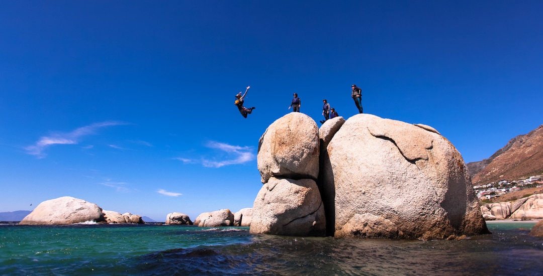 Amazing cliff jump from a giant granite boulder, coasteering with gravity Adventures, South Africa.