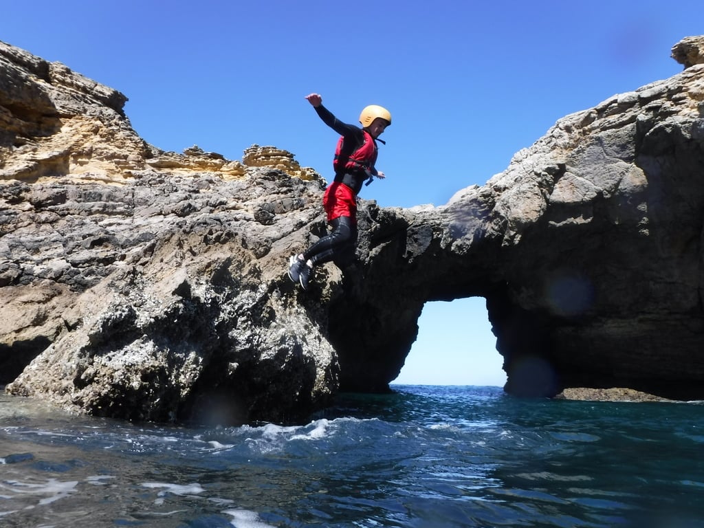 Impressive cliff jump in front of a sea arch coasteering in Portugal