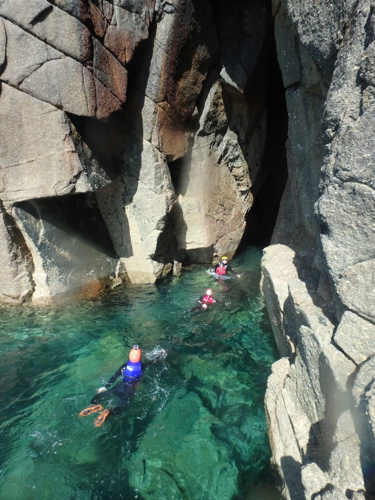 Coasteering group entering a sea cave at Land's End in Cornwall