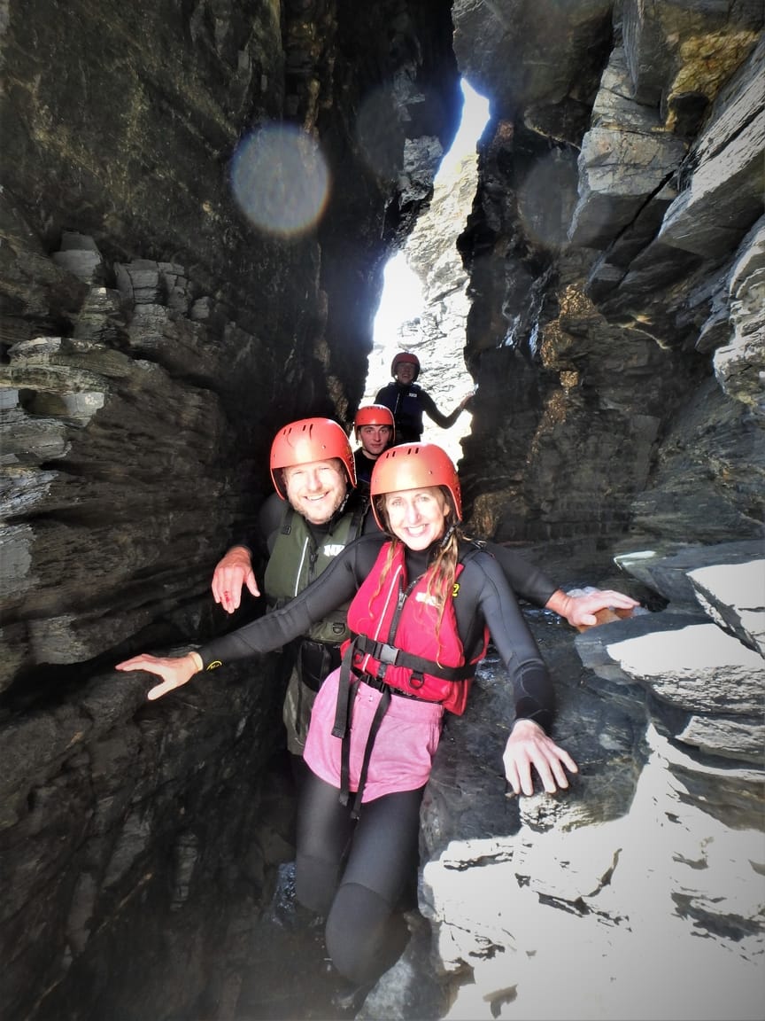 Coasteering group at Praa Sands, Cornwall going through a large crack in a sea stack on the Cornish coast.