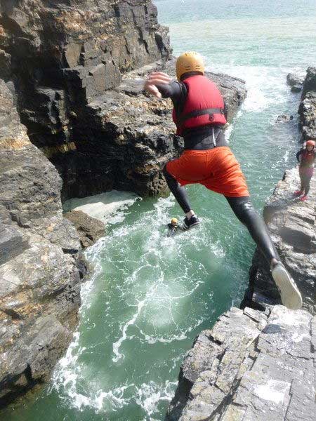 Kernow Coasteering group member jumping at Praa Sands, Cornwall, UK.