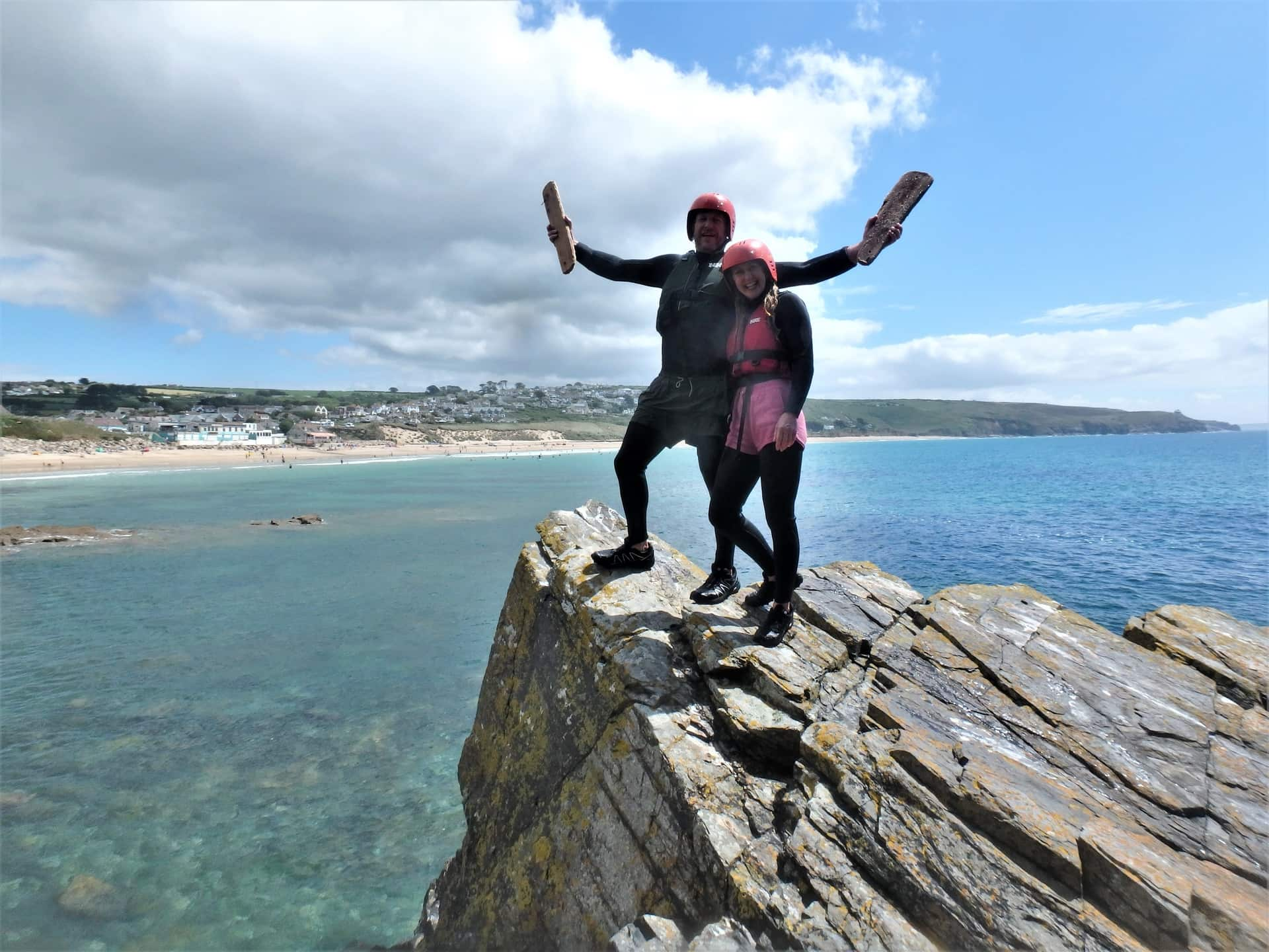 Couple posing at Praa Sands after a session with Kernow Coasteering. Praa Sands and Rinsey Head in the background.