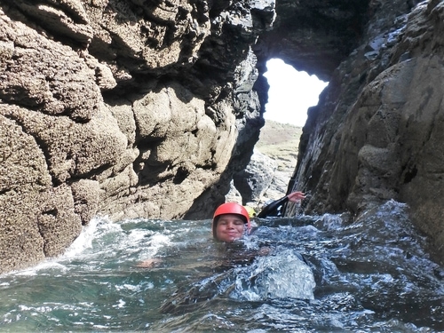 Going through a sea arch one a coasteering trip at Praa Sands.