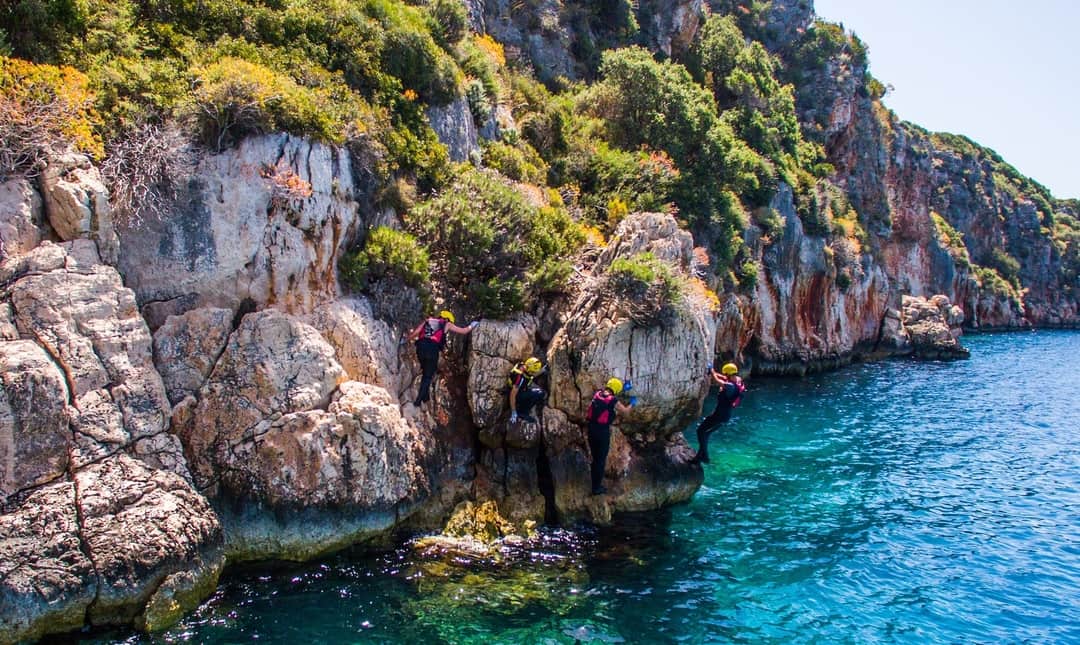 Group traversing along limestone cliffs whilst coasteering in Turkey with Dragoman