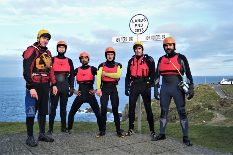 Group gathered at the iconic Land's End signpost after exploring coasteering at the end of Cornwall.