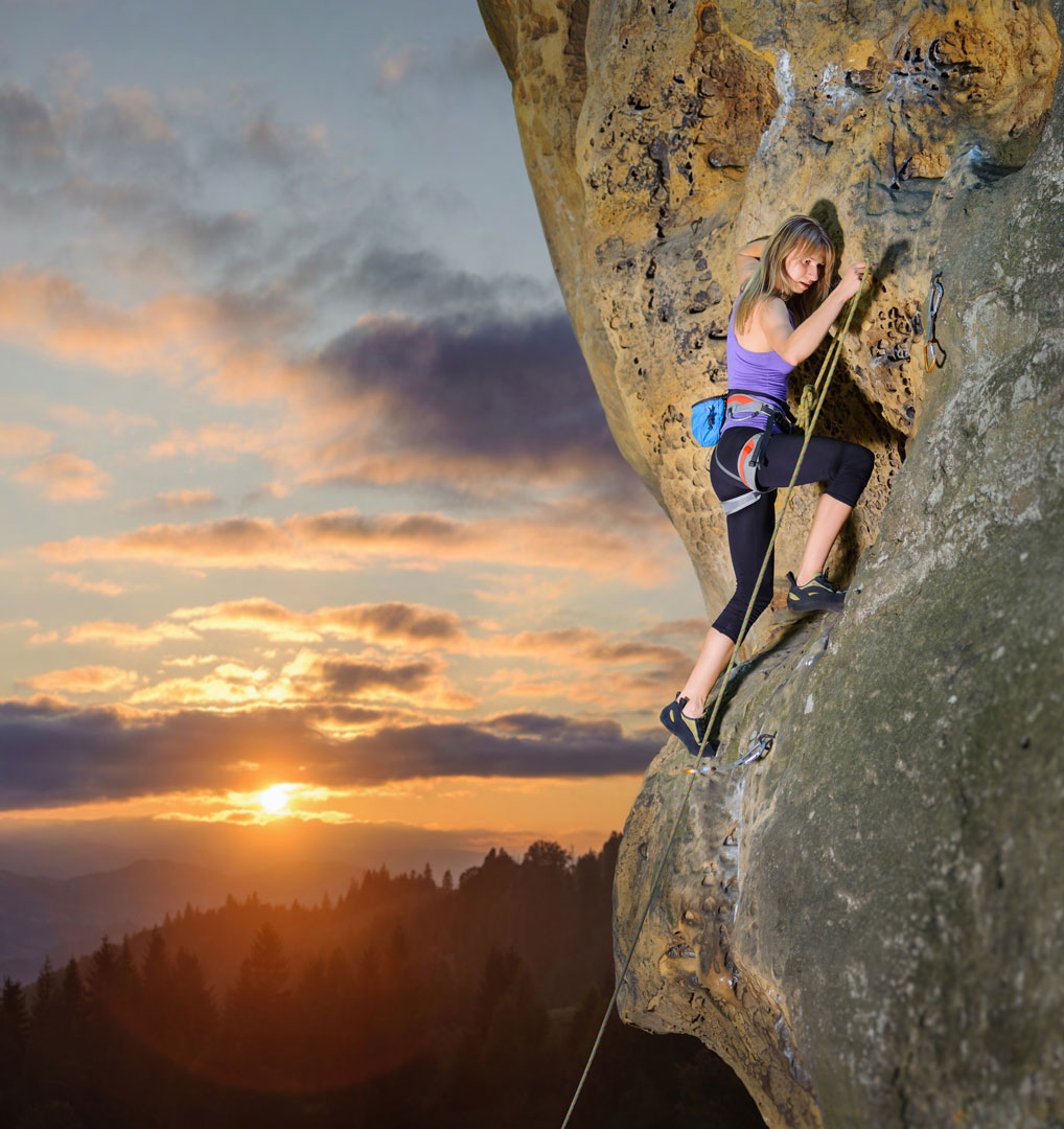 Femlae climber climbing at sunset clipping a climbing rope to a quickdraw