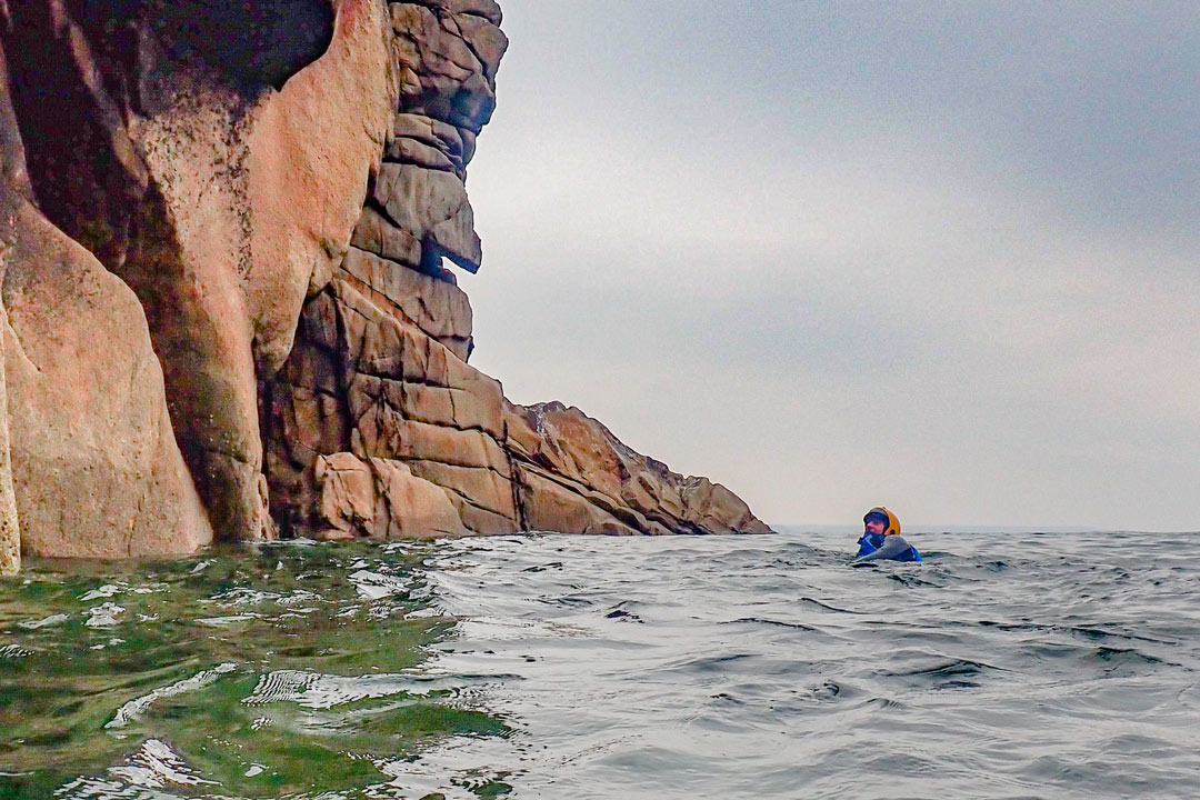 Coasteering explorer below granite cliffs near Porthleven, Cornwall