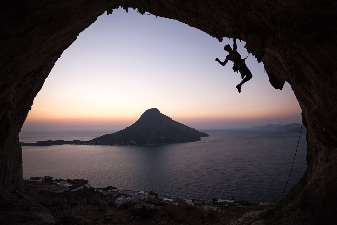 A fully equipped sport climber enjoying sunset climbing in a cave in Greece
