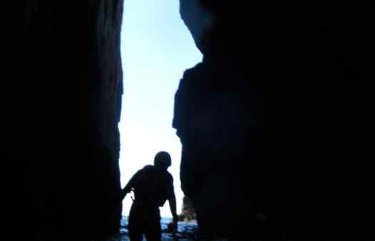 Coasteering through a large sea arch on an adventure with Kernow Coasteering, coasteering in Cornwall