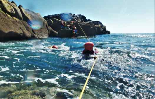 Kernow Coasteering guides using ropes to cross a choppy gully 