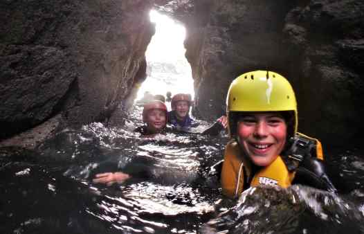 Coasteering at Praa Sands, Cornwall, going through a narrow sea arch