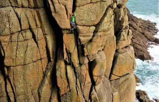 Climber enters the giant crack of Sea Horse, rock climbing in Cornwall.