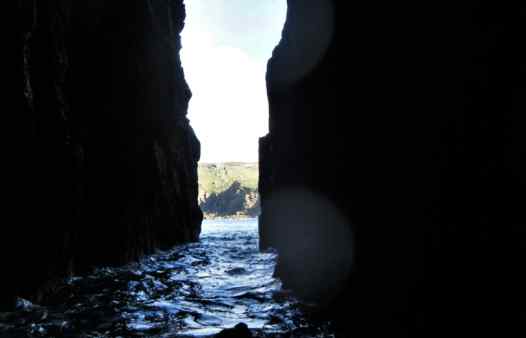 Swimming through a huge sea arch at land's End in Cornwall with Kernow Coasteering