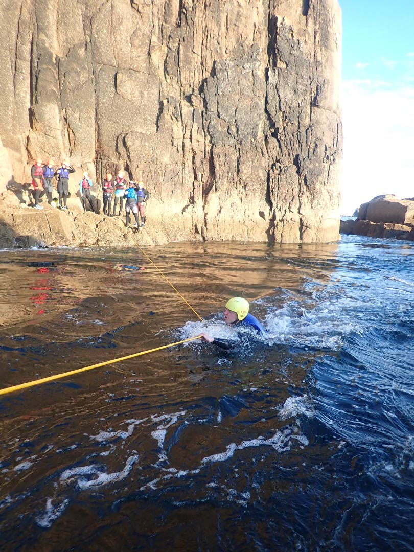 Coasteerer using a throwline to cross a strong tidal current at Land’s End, Cornwall