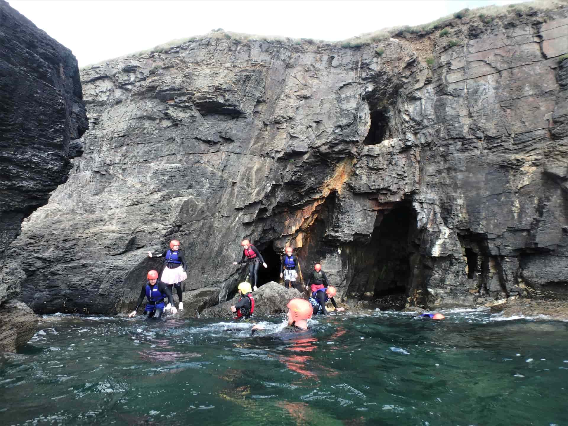Coasteering group beneath an old mine entrance at Praa Sands
