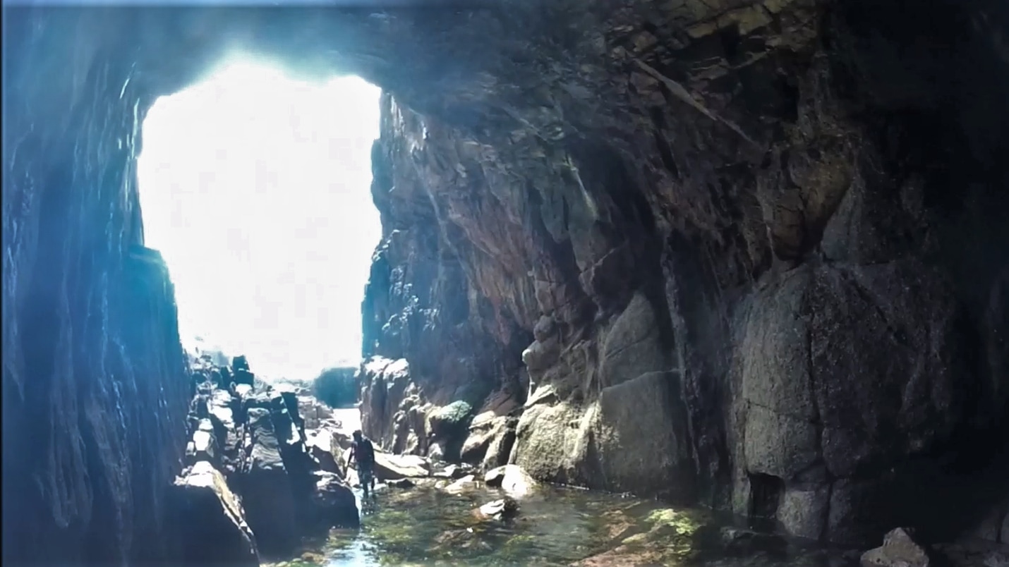 Exploring the large sea cave at Pendower Cove in west Cornwall, one of the most impressive coastal caves in the UK.