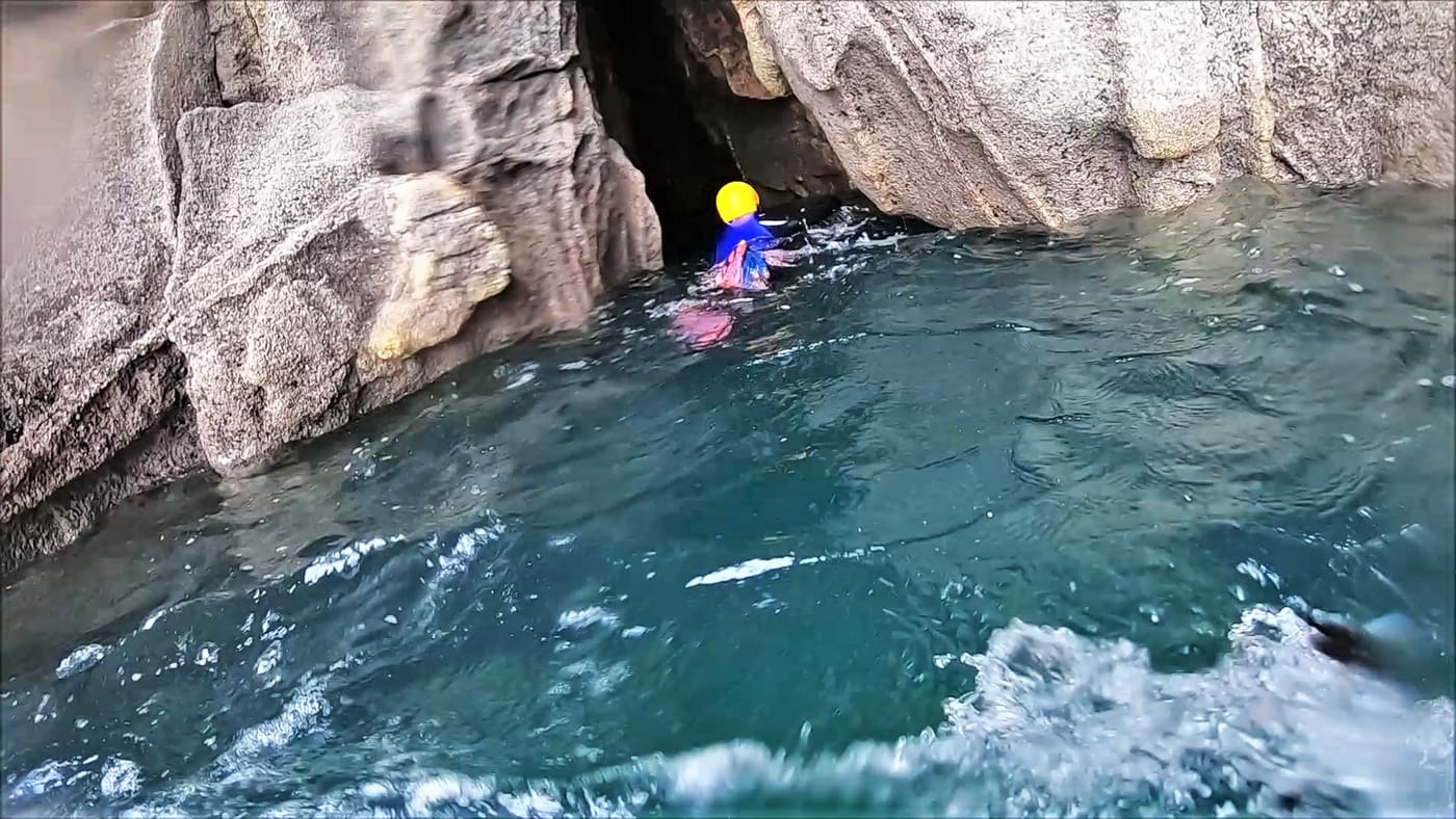 Coasteering towards the narrow entrance of a coastal cave beneath Rinsey Head in Cornwall.