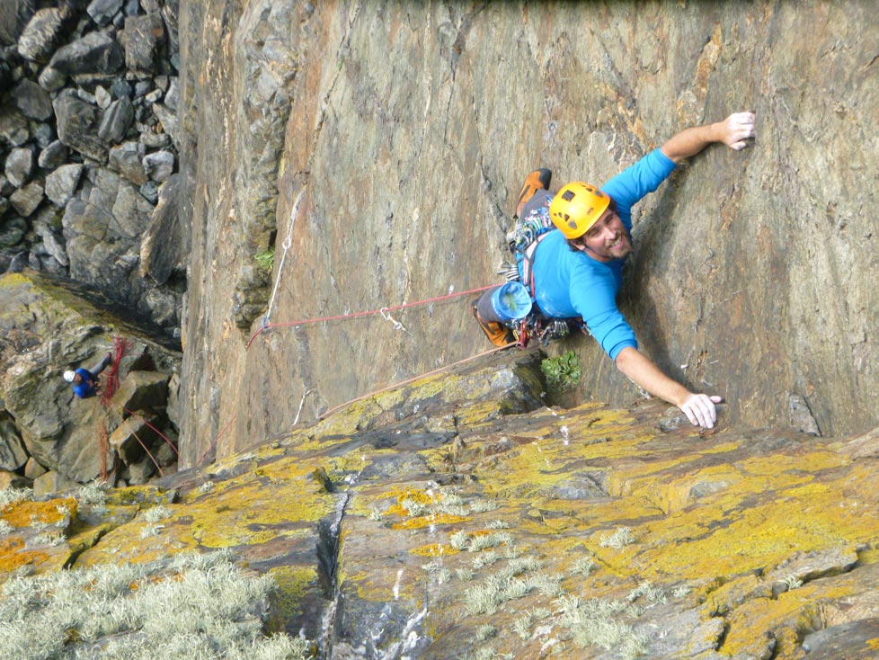 Climber leading a trad route at Kenidjack, Cornwall, wearing a Petzl helmet – one of the best climbing helmets for trad.