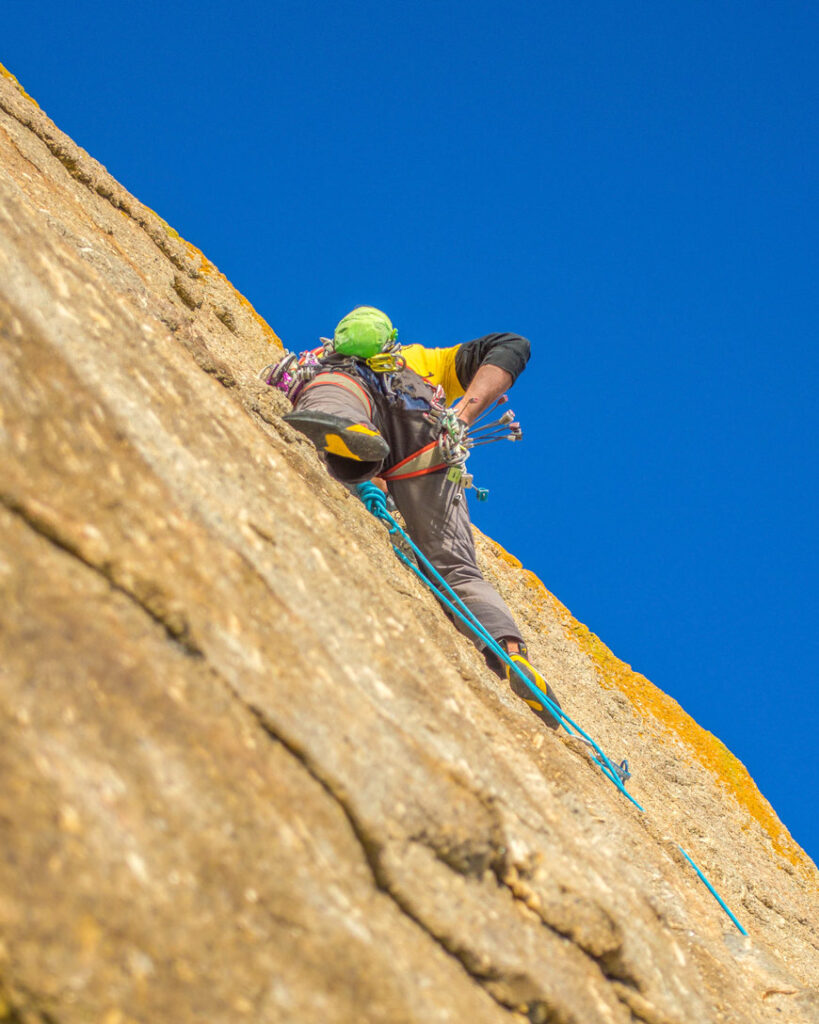 Trad climber placing nuts on a granite face during lead climb.