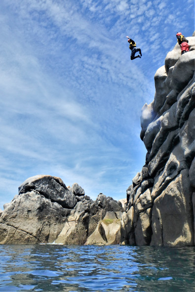 Person leaps from granite cliffs into the sea on a coasteering trip – the ultimate outdoor adventure Cornwall offers for thrill-seekers and lovers of adventure activities Cornwall