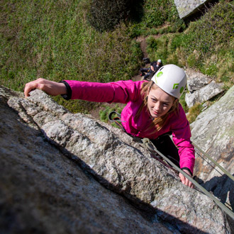 Beginner climber trying hard on a guided climbing Cornwall experience.