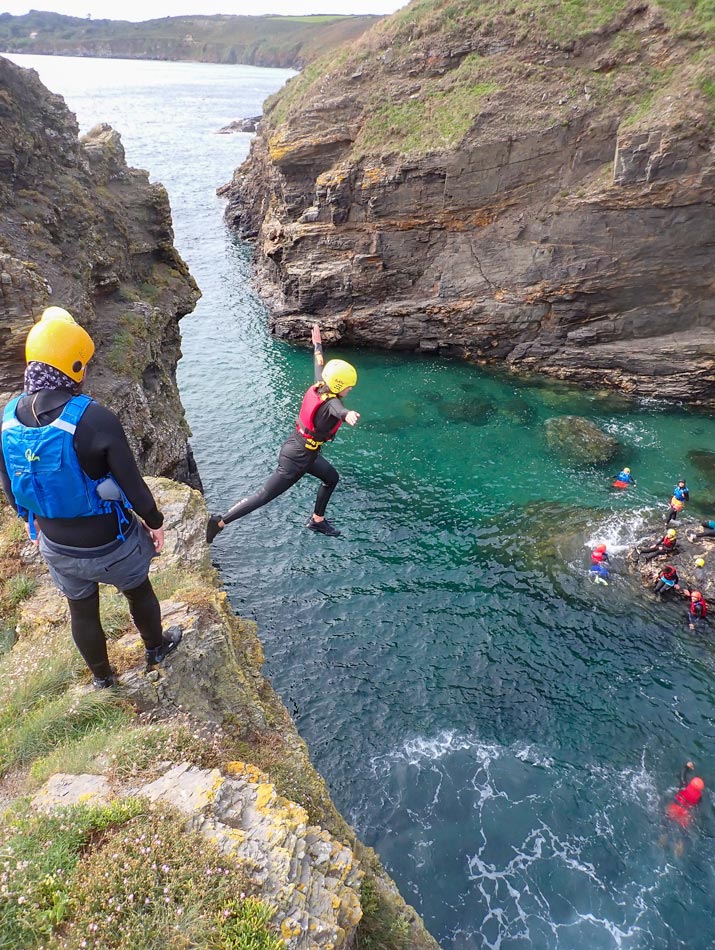 Participant performing a stylish cliff jump during a coasteering session in Cornwall.