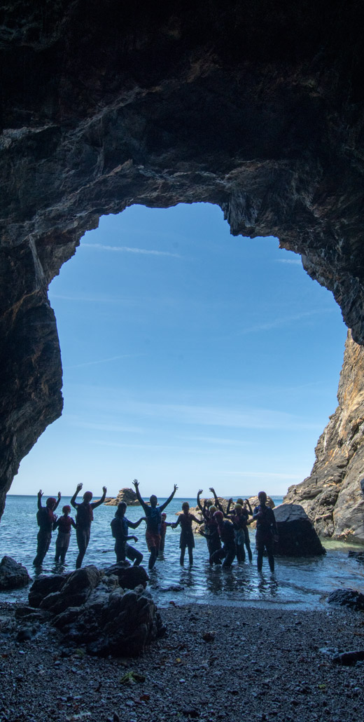 Group standing in a sea cave on the Cornish coast during a coasteering adventure.