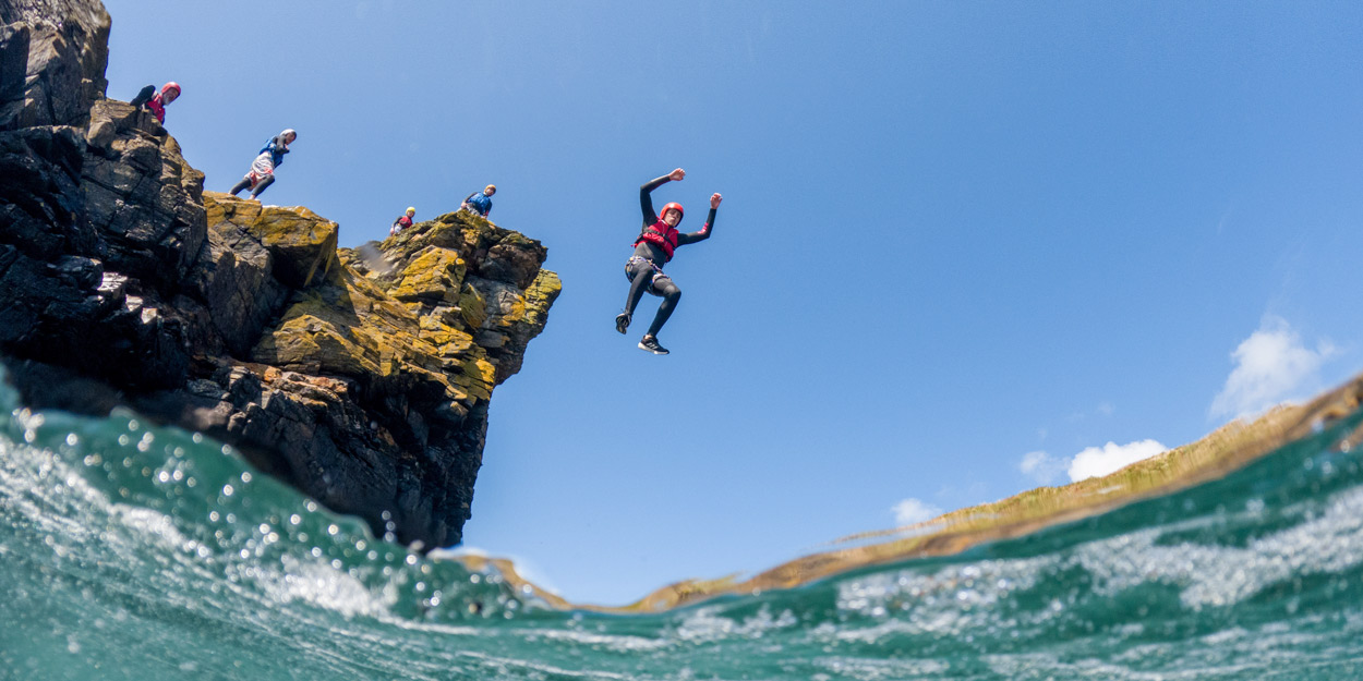 Group coasteering and cliff jumping into the sea along the Cornwall coast – an unforgettable outdoor activities Cornwall experience and one of the most fun things to do in Cornwall