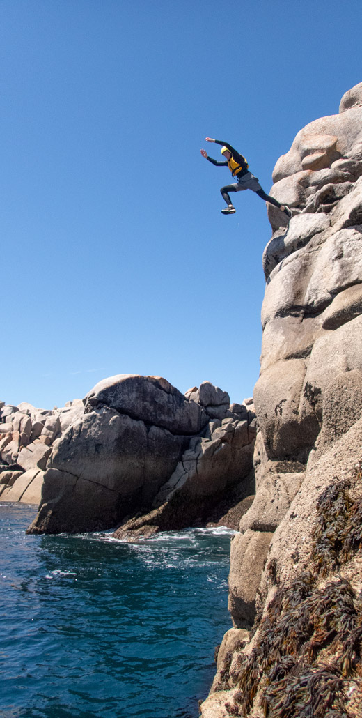 Teenager doing a massive cliff jump in the Isles of Scilly. A thrilling adventure near Hugh Town on St. Mary's.