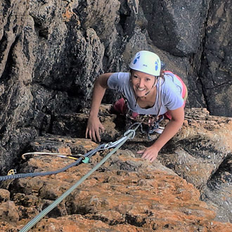 Intermediate climber on granite sea cliffs during a guided climbing Cornwall session with a climbing instructor Cornwall.