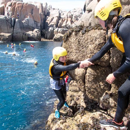 Is coasteering safe? Group helping each other to have a safe coastal adventure