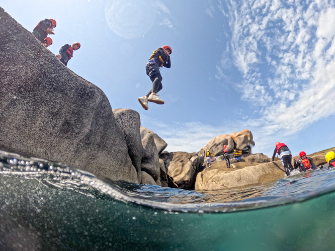 Young person cliff jumping in white-water on St. Mary's. A thrilling adventure for kids seeking outdoor excitement on Scilly.