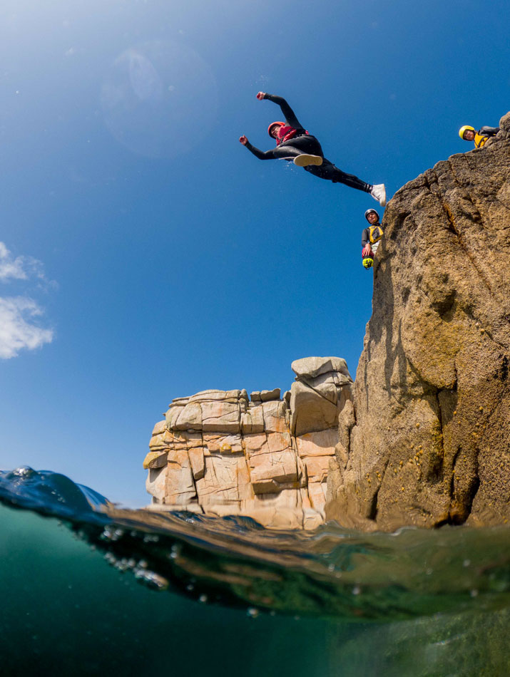 Adventurer cliff jumping into the clear waters, starting their Scilly Isles holiday in style.