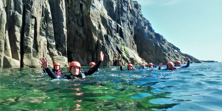 Group of coasteerers swim through an isolated zawn at Dollar Cove, part of the Land’s End route