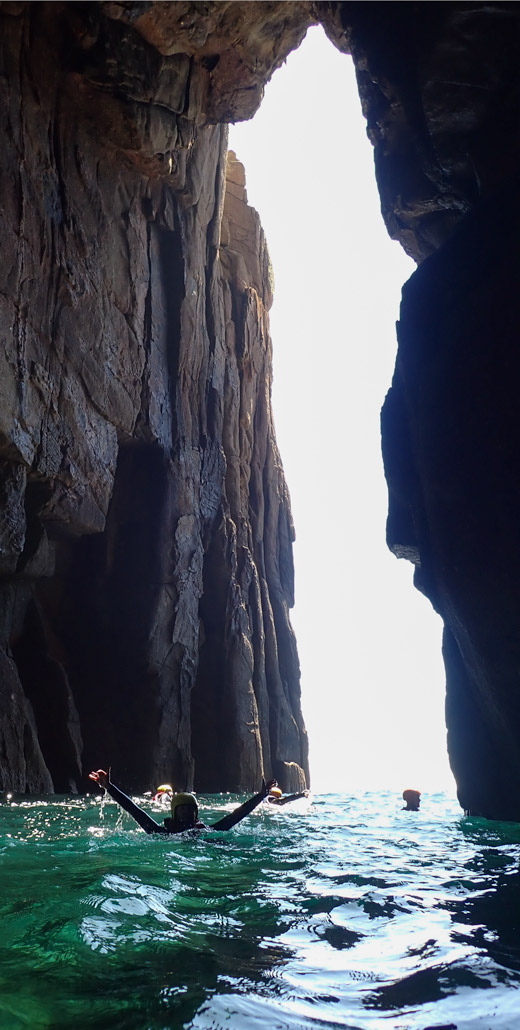 Coasteerers swim through Land’s End Hole, a giant sea arch cut through Dr. Syntax’s Head