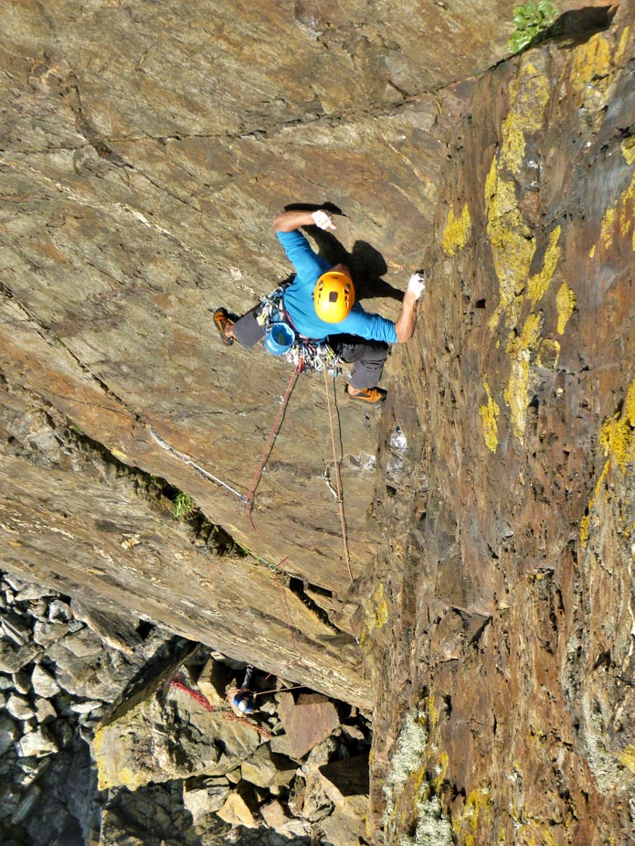 A climber leads Thane (E1) at Kenidjack on the steep granite cliffs of Cornwall, demonstrating expert technique and rope skills