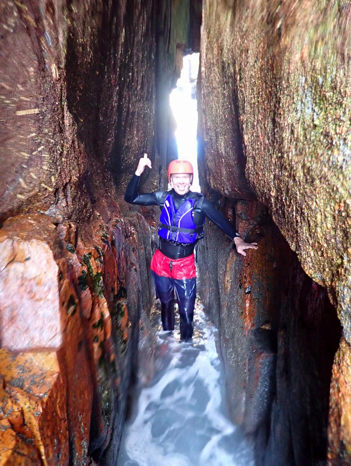 Coasteerer traverses the golden-lined sea arch near Dr. Syntax’s Head at Land’s End