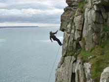 Climber on the granite sea cliffs at Trewavas, a popular location for beginner rock climbing Cornwall sessions