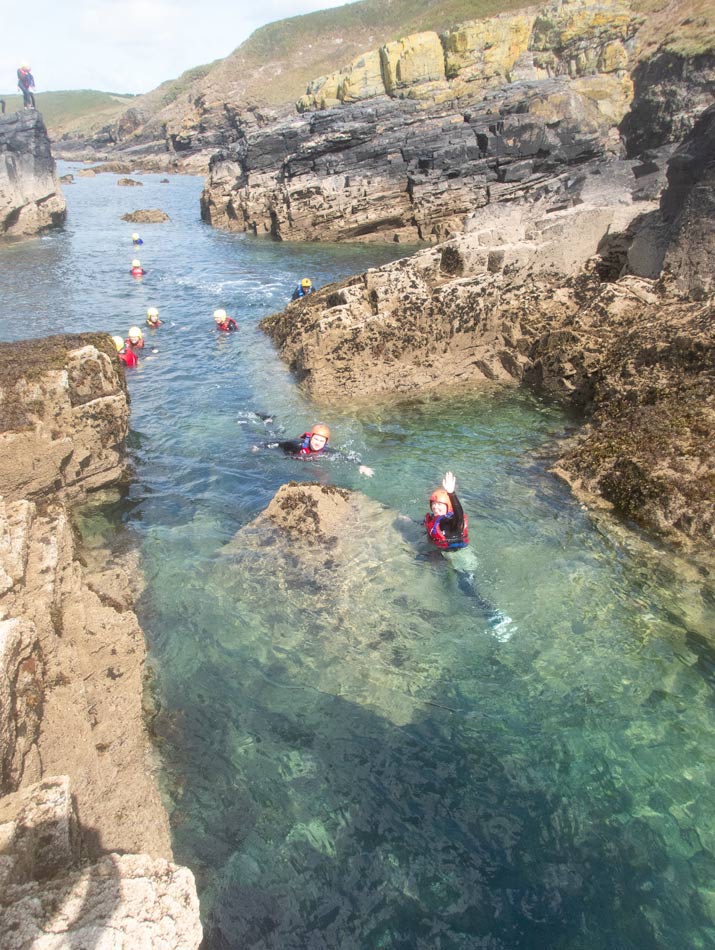 Family group explores rock formations at low tide near Penzance on a guided coasteering route