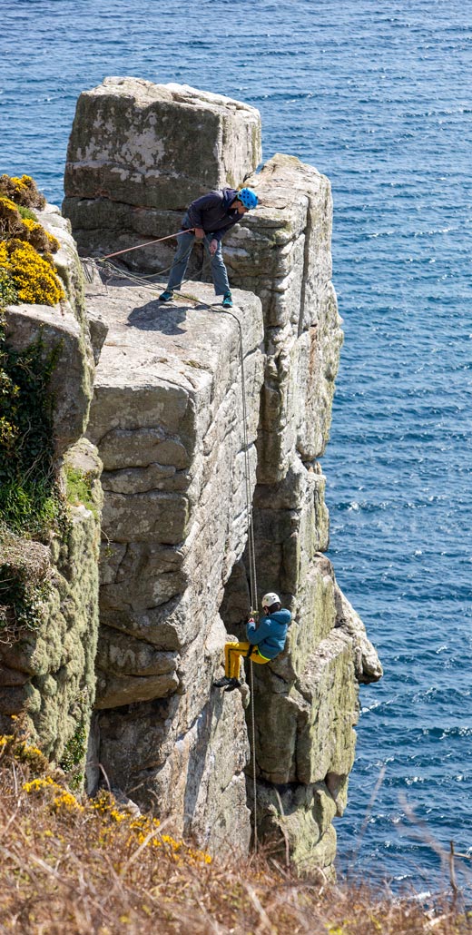 Young climber abseiling with instructor guidance on a sea cliff at Trewavas
