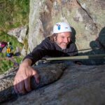 Beginner climber making their way up a granite route in Cornwall