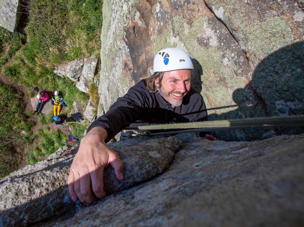 Beginner climber making their way up a granite route in Cornwall