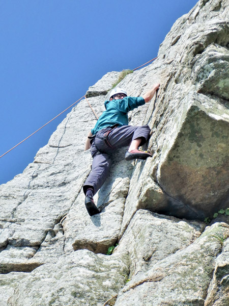 Beginner climber ascending granite face at Trewavas Head in Cornwall